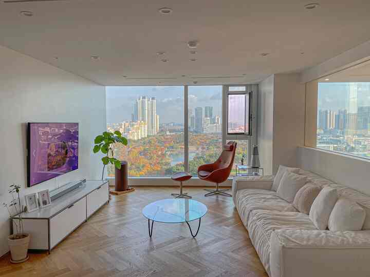 Minimal living room with white and natural tones featuring a large window and modern armchair creating a cozy atmosphere