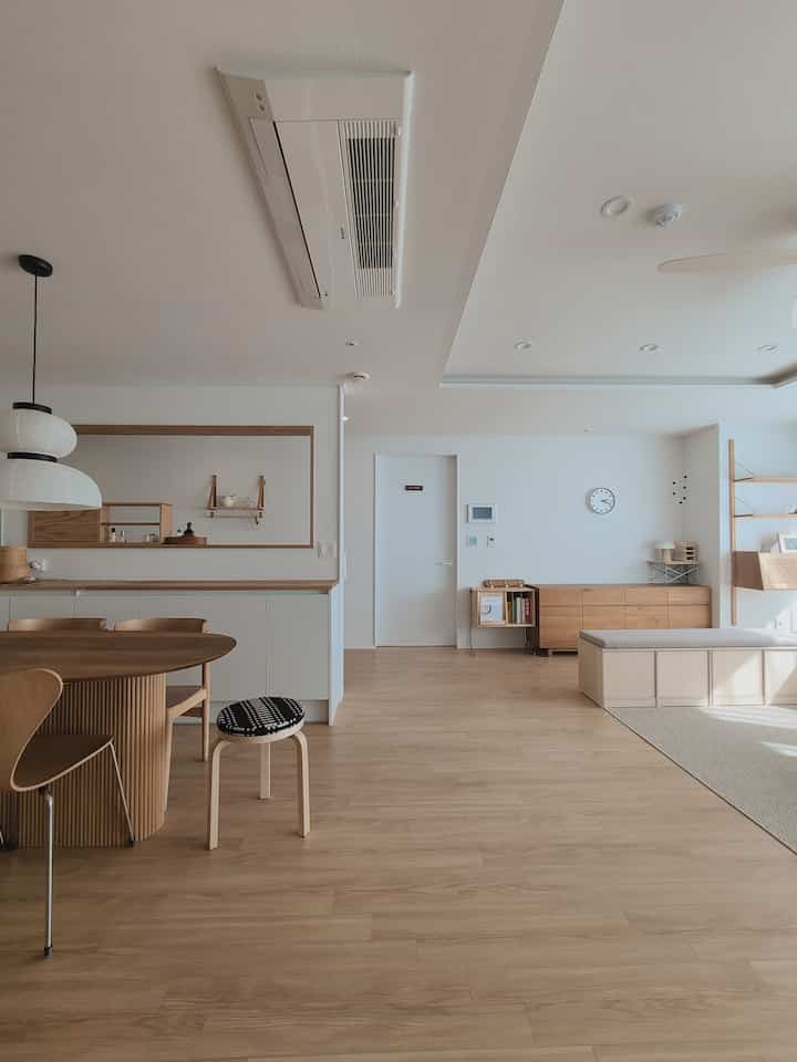 Natural tone dining room featuring wooden dining table and chairs, beige bench, with clean minimalist interior