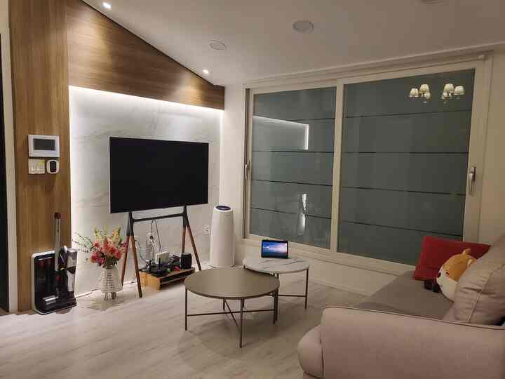 White and wood tone living room for single household, featuring sofa, TV, and coffee tables in a modern setting