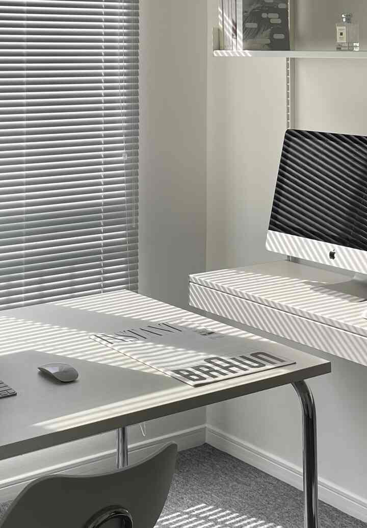 White-toned home office workspace featuring an iMac and blinds creating a sleek atmosphere