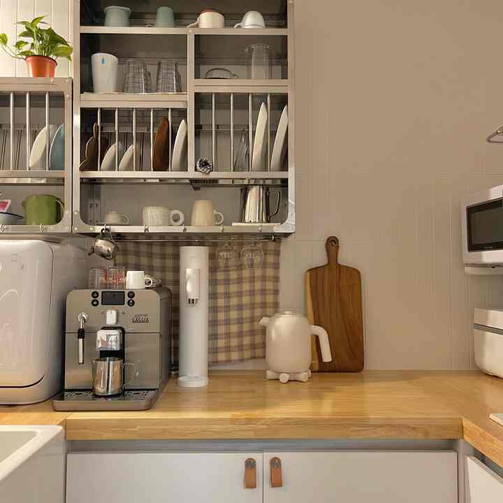 White and natural wood tone kitchen featuring a coffee machine and kitchen accessories centrally placed, neat home cafe atmosphere