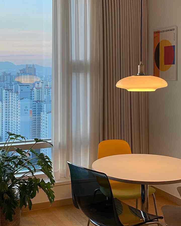 Modern dining room in white and natural tones, featuring yellow and transparent chairs around a round table