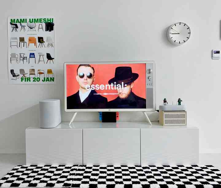 Modern living room dominated by white and black checkerboard rug, featuring a sleek TV and minimal decor at center