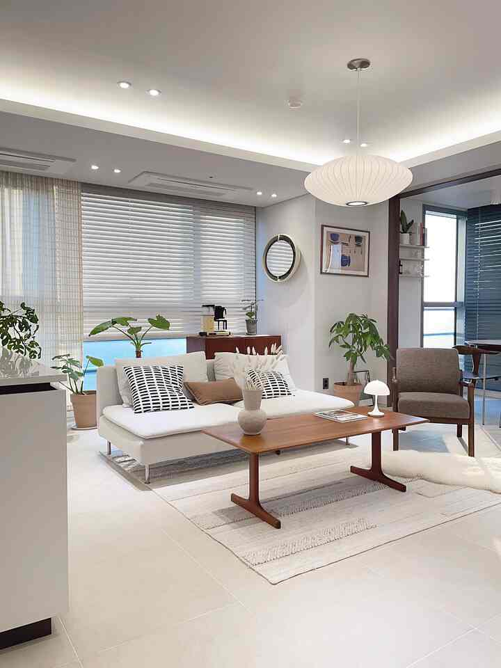 白を基調とした北欧スタイルのリビング、ナチュラルな木製家具と居心地の良いソファ、落ち着いた間接照明が配された印象的な空間