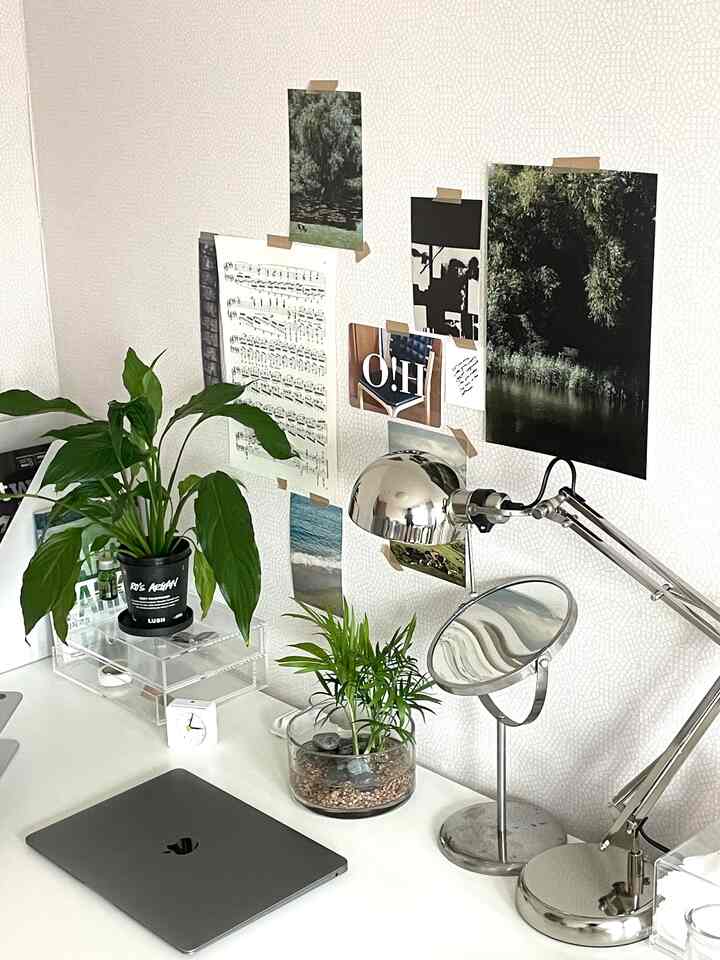 白を基調としたホームオフィス、植物やポスター、メタリックのテーブルランプが配置された印象的な空間