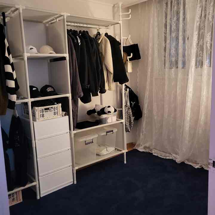 白いマルチハンガーとネイビーのラグがあるウォークインクローゼット、レースカーテンで柔らかな雰囲気のあるインテリア