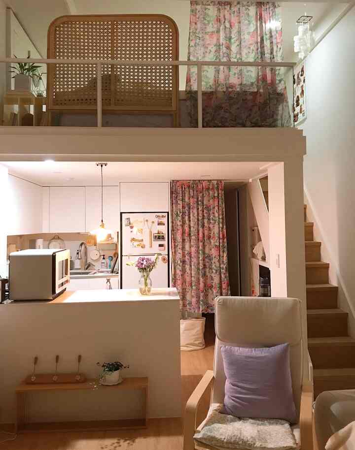 温かい照明とヴィンテージローズのカーテンが映えるナチュラルトーンのロフトリビングインテリア