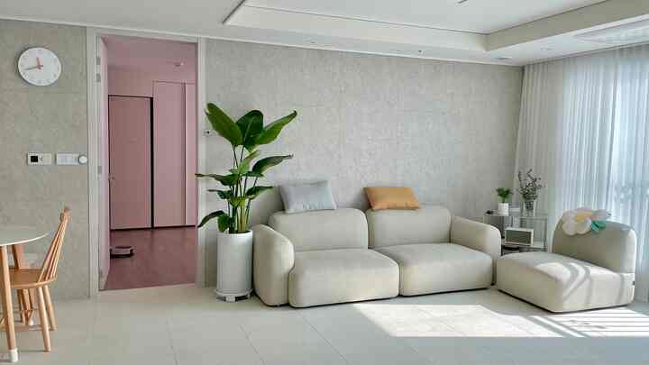 Bright and cozy living room in white and natural tones, featuring a modular sofa and round dining table