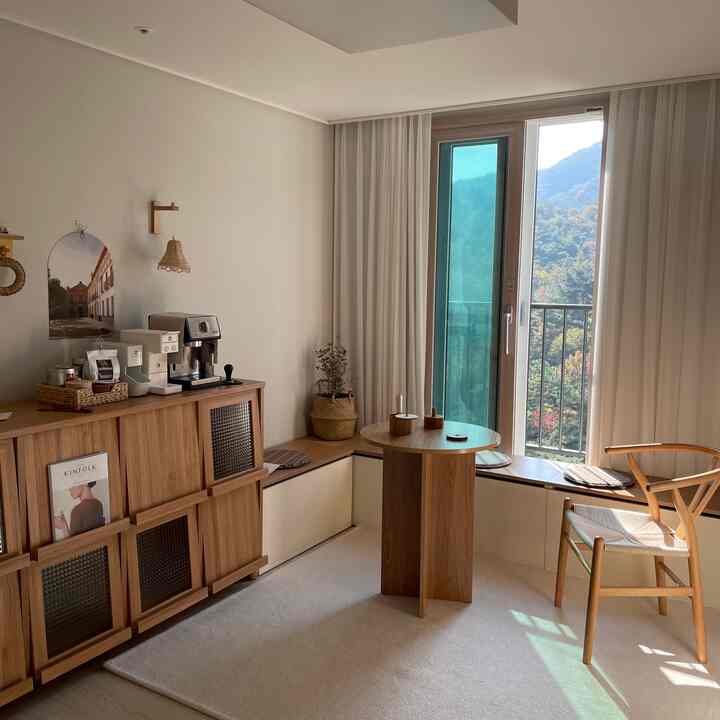 Natural wood tones and white curtains in a home cafe room featuring a round table and bench, creating a cozy atmosphere
