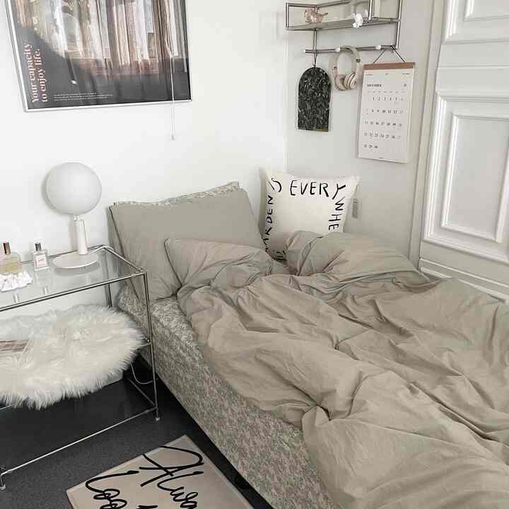 ナチュラルカラーとホワイトのトーンのコンパクトな寝室、ベージュの寝具と金属製ナイトテーブルが調和するモダンなインテリア