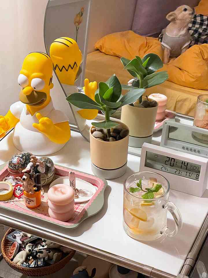 イエローとマスタードトーンのソファがあるリビングルーム、鏡と小さな水耕植物が置かれたホワイトテーブルの上にレモネードの入った透明なマグカップが配置された雰囲気のある空間