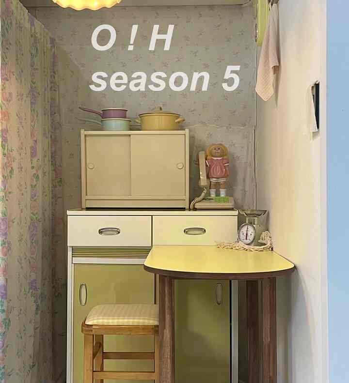 ベージュとライトブラウンのトーンが特徴的な狭いヴィンテージ風キッチン、小さなテーブルとキッチンスケールが配置された雰囲気のあるインテリア