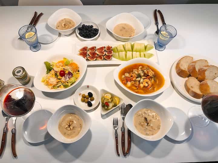 Minimal and modern dining table in white tone featuring diverse plates and wine glasses for a home party setting