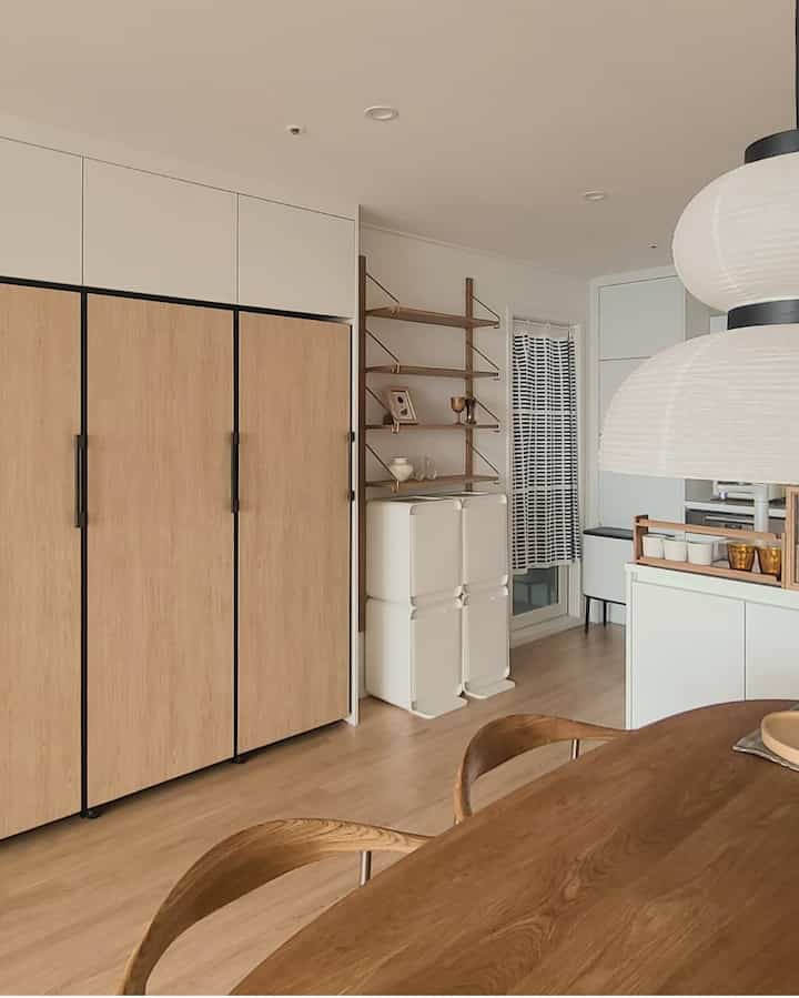 Wood tone and white kitchen with dining table and chairs, featuring clean and natural atmosphere