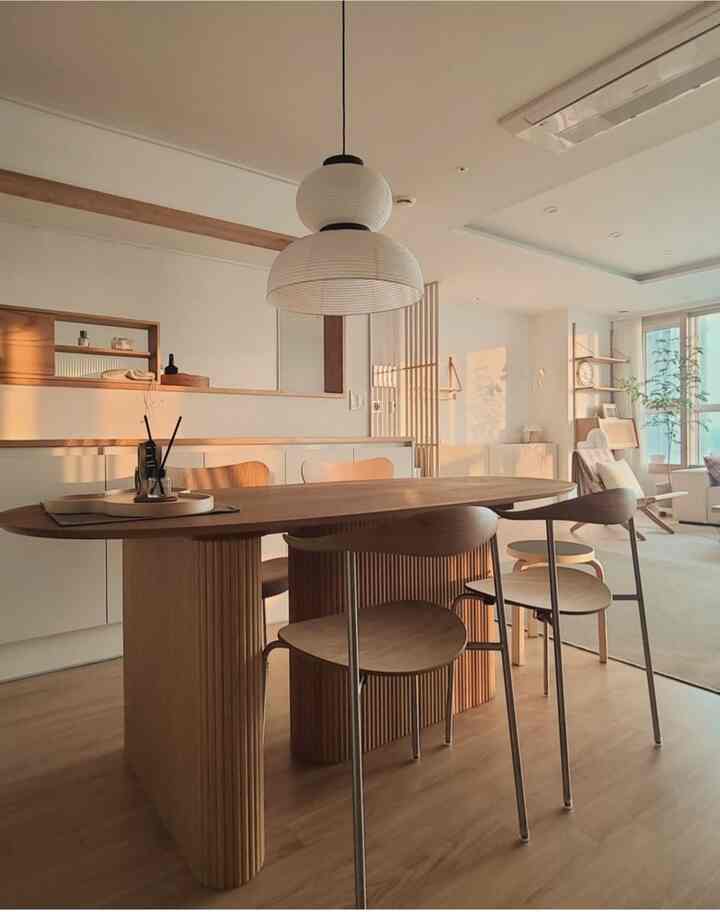 Natural-toned living and dining space featuring a wooden dining table, chairs, and pendant lighting in a modern interior