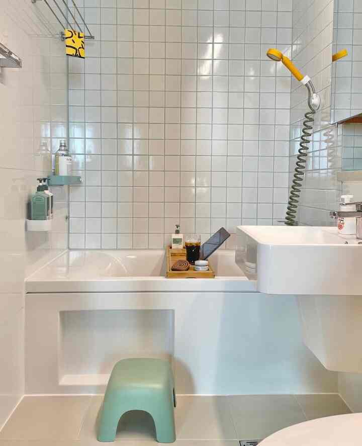 White and yellow toned bathroom featuring tiled walls and bathtub in a simple, clean space