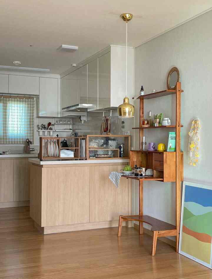 ナチュラルな木目調とゴールドのペンダントライトがあるシンプルなキッチン、すっきりとしたキャビネットと棚が配された雰囲気のあるインテリア