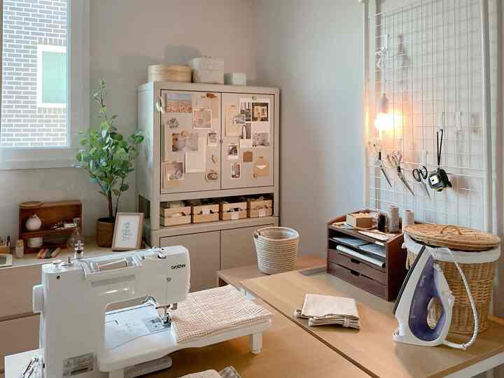 Cozy workspace in light beige and wood tones featuring a metal cabinet, sewing machine on table, and warm lighting