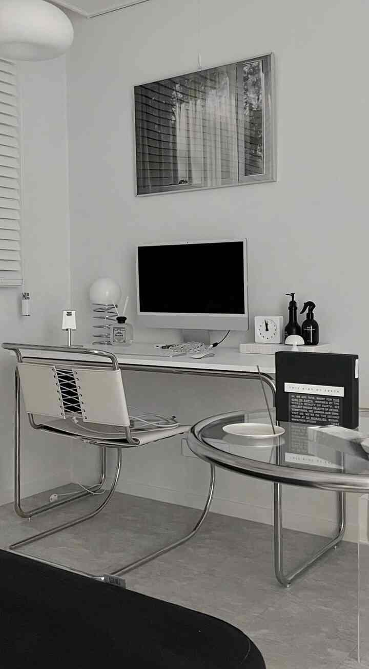 白とグレーのトーンのホームオフィス、シンプルでモダンなデスクとチェアが配置された落ち着いたインテリア