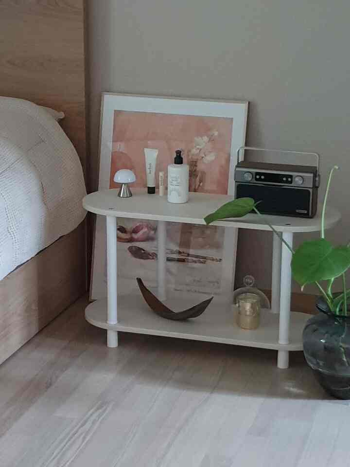 Natural-toned bedroom featuring a white nightstand and green plant with a cozy modern atmosphere