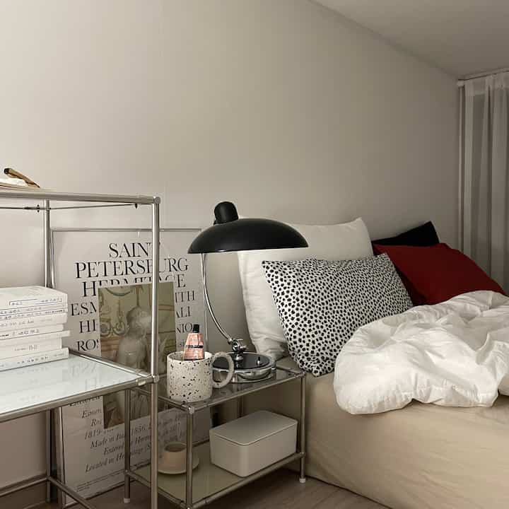 Modern bedroom in white and black tones featuring metal shelving and diverse pillows with cozy atmosphere