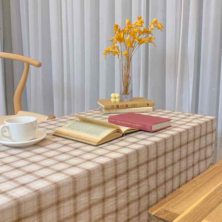 Dining room with white curtains and beige check tablecloth, natural wood furniture creating warm and cozy atmosphere