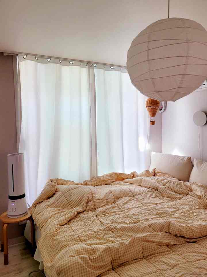 Cozy bedroom featuring warm beige checkered bedding and white blackout curtains, designed for living with a baby