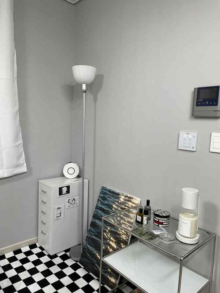 Modern small room corner with white and gray tones featuring a storage cabinet and metal shelving unit
