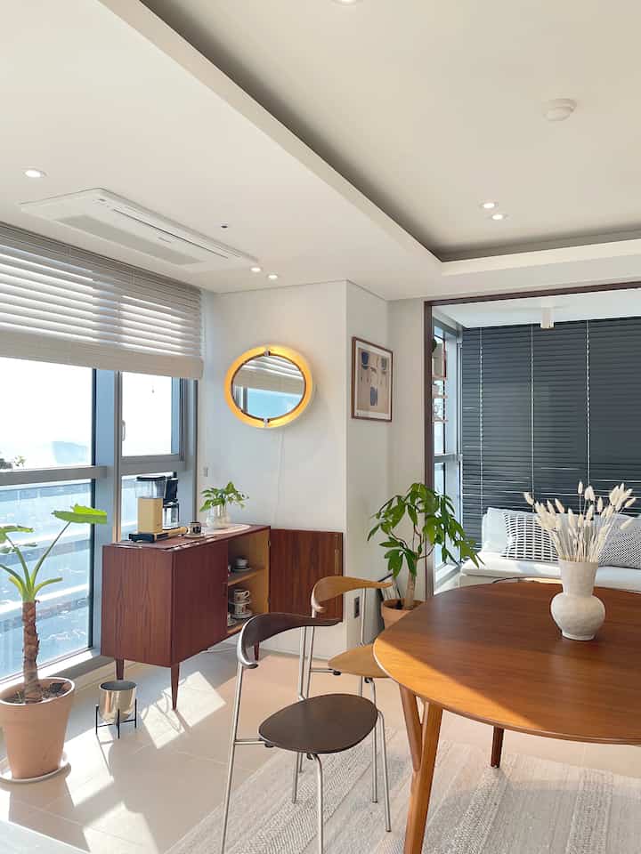 Warm brown wooden dining table and white walls blend in a vintage style living room filled with sunlight and cozy atmosphere