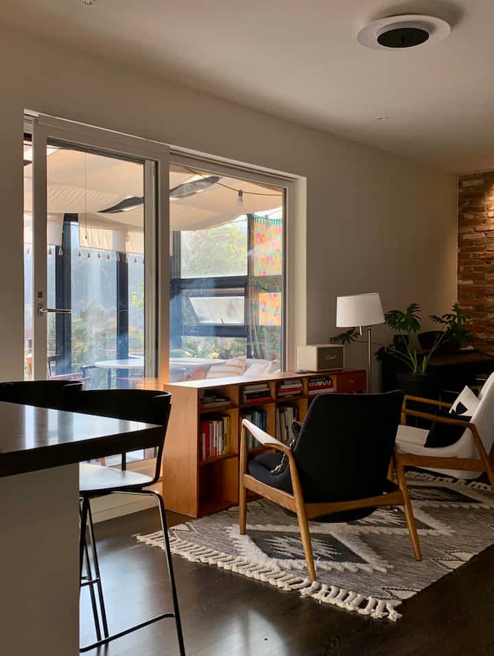 Cozy small living room with wood tones and white, featuring armchairs and a low bookshelf in a natural modern style