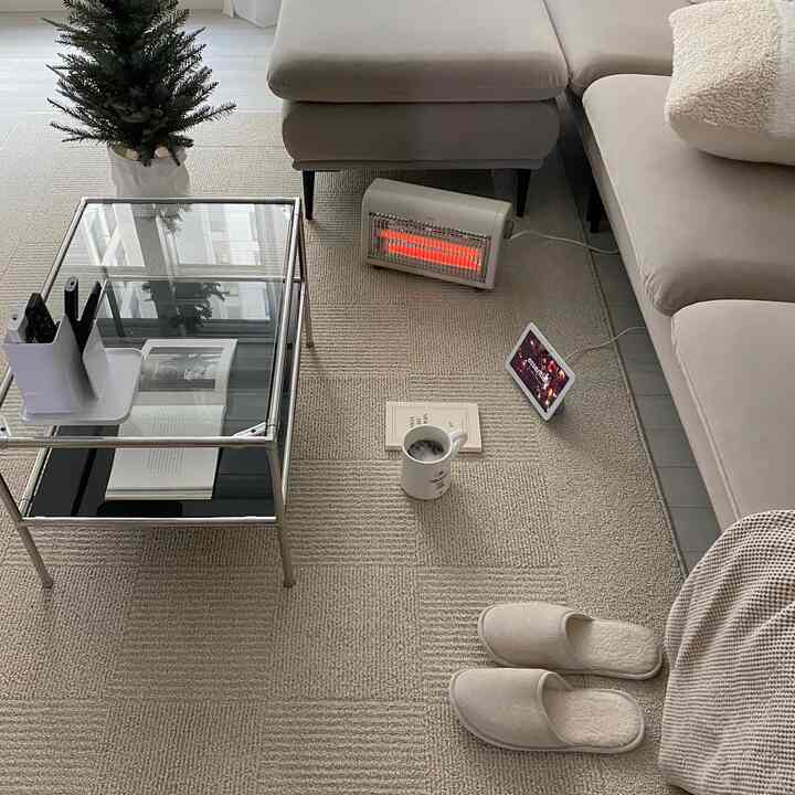 Cozy natural color living room featuring beige sofa, electric heater, and glass coffee table in warm minimalist style