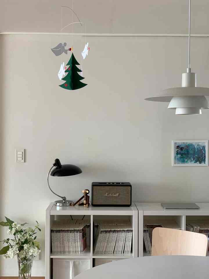 White and natural toned living room featuring bookshelf, Artek chair, and pendant light with a modern atmosphere