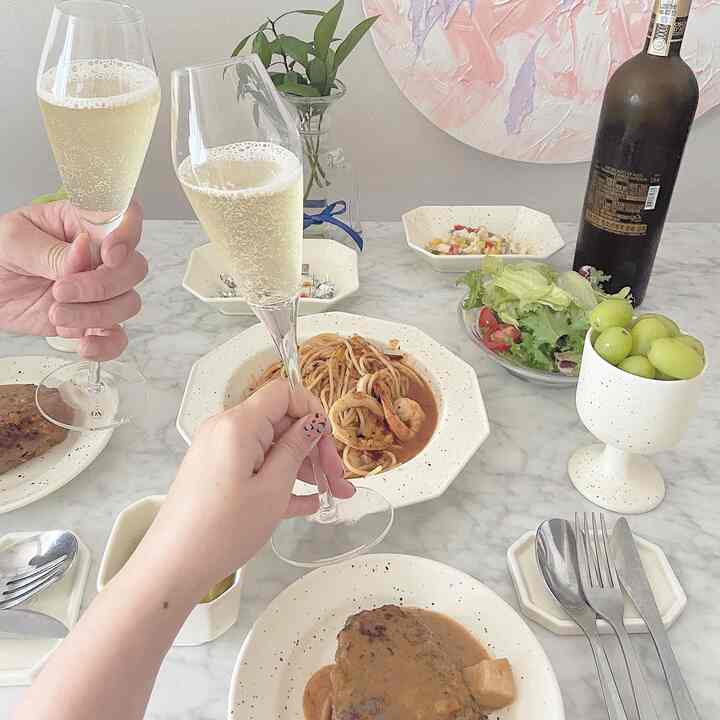 白を基調としたダイニングルーム、中央の大理石のダイニングテーブルに皿やワイングラス、料理が配置された雰囲気のあるインテリア