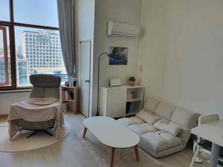 Ivory-toned male studio living room featuring a recliner, low sofa, and white coffee table in a simple, clean space