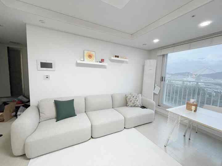 White-toned living room featuring a rounded modular sofa and table runner in a clean, bright space