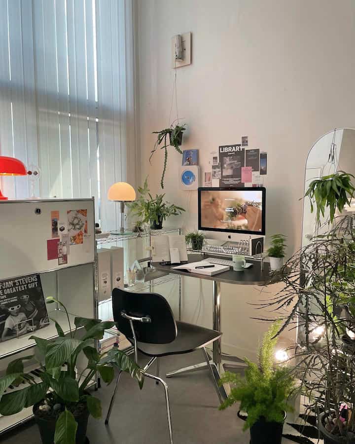 White and black toned home office featuring a desk, computer, and ample plants with a clean modern atmosphere