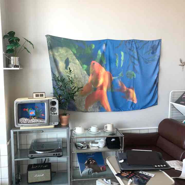 ブルーとブラウンのトーンのリビング、ヴィンテージテレビ形の水槽とブラウンレザーソファが配置された落ち着いた空間