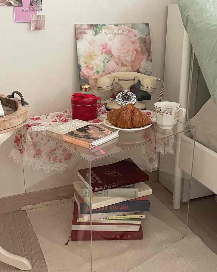 Bright beige and white toned bedroom featuring transparent acrylic side table and vintage telephone in a cozy setting