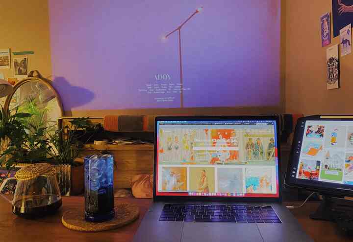 Warm beige toned home office workspace featuring a desk with laptop and tablet, cozy room with projector screen on the wall