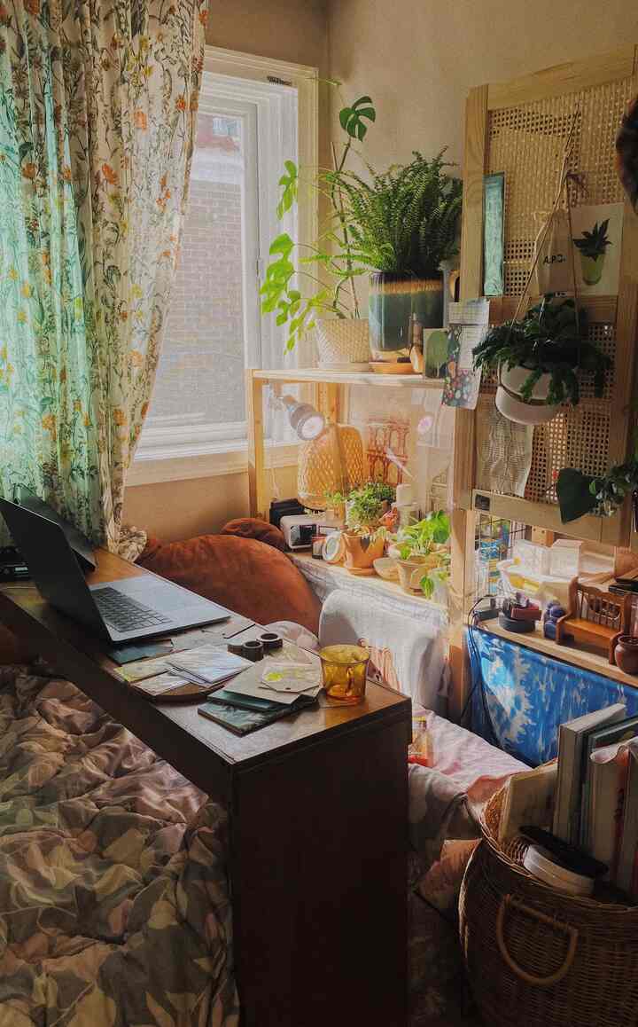 Warm beige bedroom workspace featuring floral linen curtains and various plants creating a cozy atmosphere