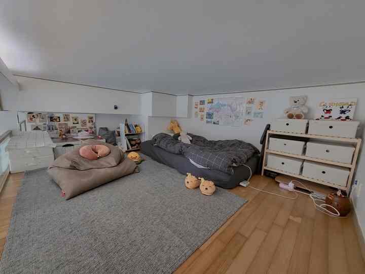 白とグレーのトーンが特徴のロフトの子供部屋、ラグやマットレス、収納が配置された雰囲気のあるインテリア