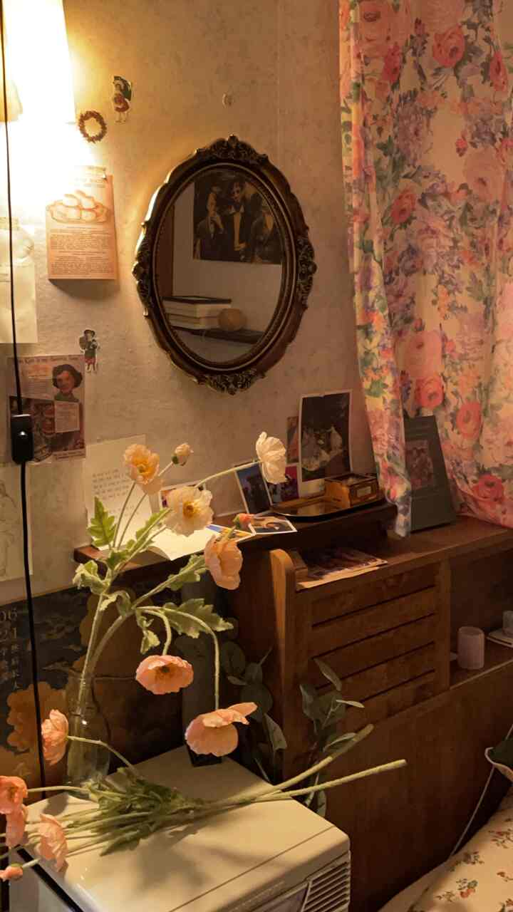 Soft beige-toned wall vintage style interior with an ornate decorative mirror, floral curtains, and a vase with flowers in a cozy bedroom area