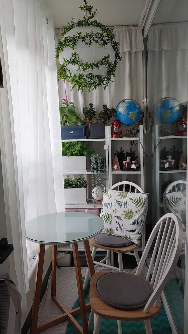 White and natural tone veranda featuring plants and a pendant light in a cozy small relaxation space