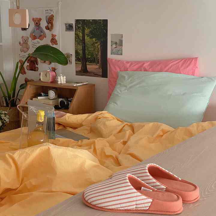 Beige-toned bedroom with natural wood furniture, featuring yellow bedding and pink cushions creating a warm atmosphere