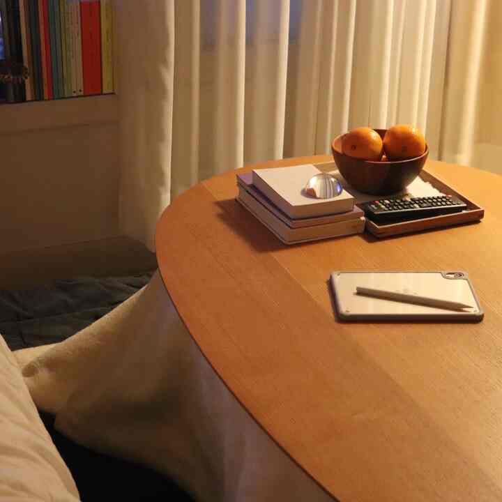 暖かい木目調と白いカーテンのリビング、こたつとブランケットが居心地の良い雰囲気を演出する空間