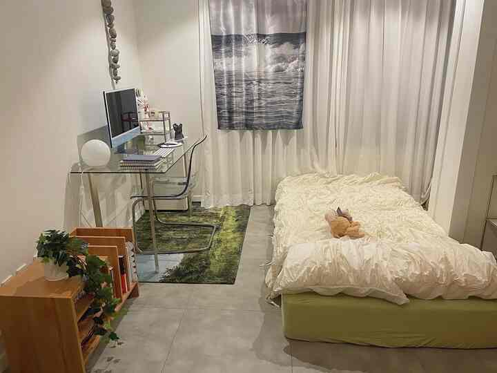 Natural-toned studio bedroom featuring a transparent glass desk and neat bed in a modern space
