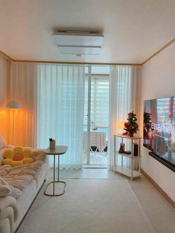 White and beige toned living room featuring a large sofa, side table, and warm lighting creating cozy atmosphere
