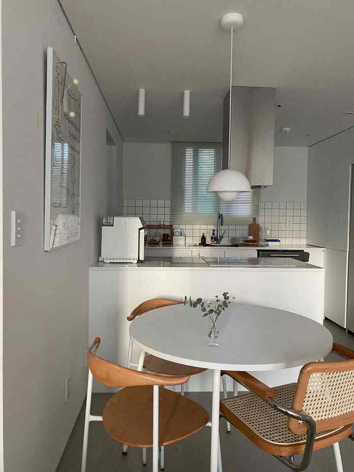 白と木目調が調和したキッチンと円形ダイニングテーブルが配置されたシンプルで自然な雰囲気のインテリア