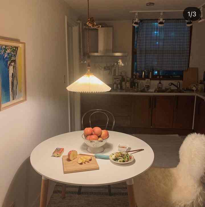 Warm cafe style kitchen-dining space with white walls and wooden cabinetry, featuring a round dining table and two chairs