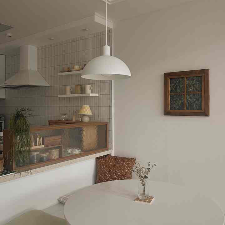 白とナチュラルブラウンのトーンが調和したキッチン、円形テーブルと収納ベンチが配置された雰囲気のあるおうちカフェインテリア